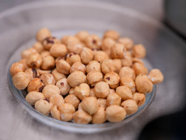 Shelled hazelnuts gathered in a shallow glass dish.