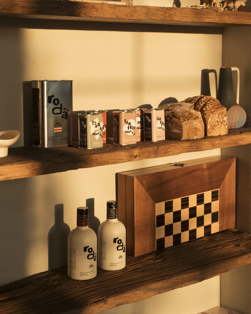 Shelves of olive oil tins, spice packets and bread loaves in a small grocer.