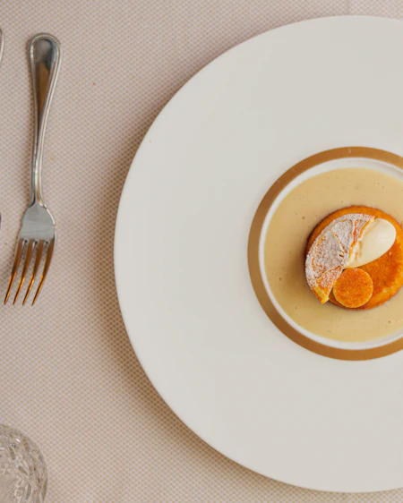 Citrus curd with olive oil crumb plated on a gold-rimmed cream dish, seen from above.